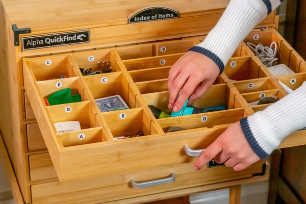 Hand placing an item in a lettered compartment of an Alpha QuickFind drawer